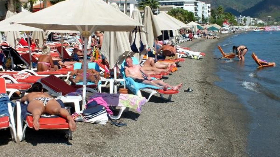 Bikinili turistleri buzlu suyla serinleten garson